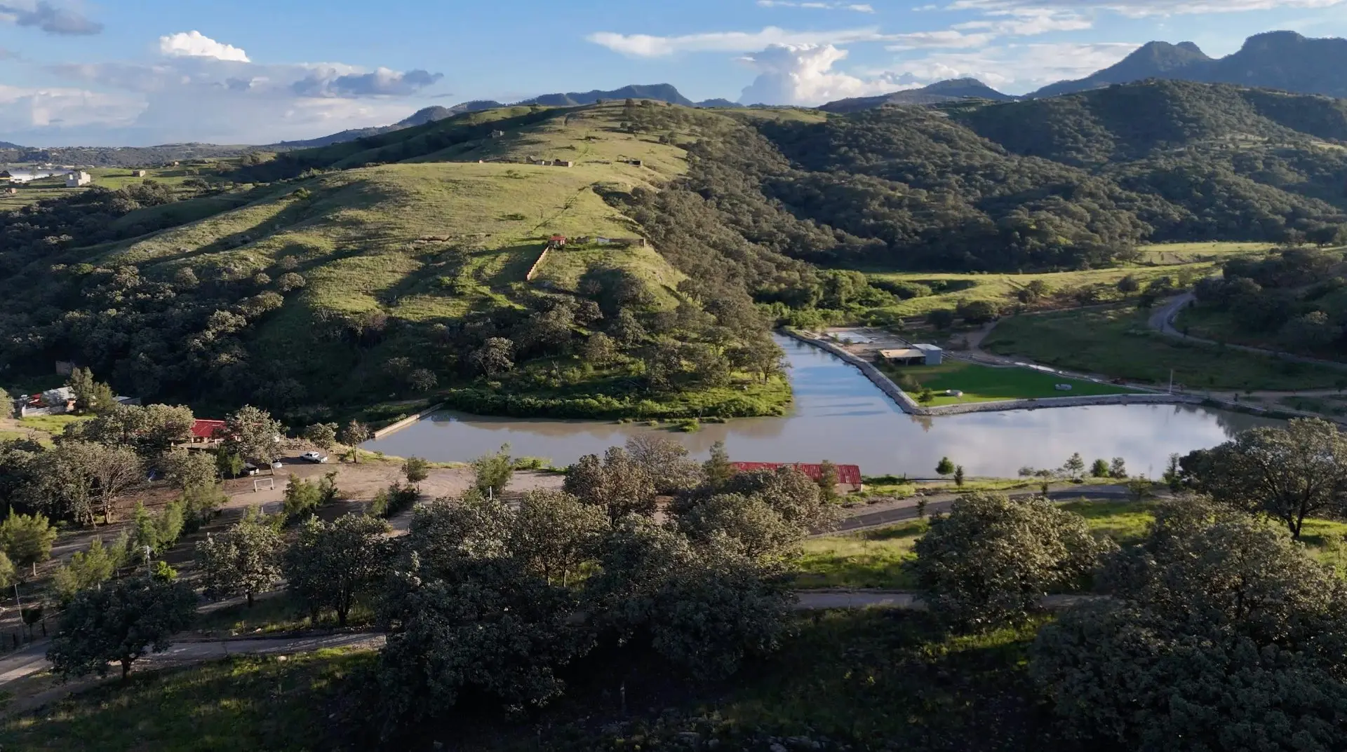 Paisaje de Tierra Viva con lago, áreas verdes y montañas